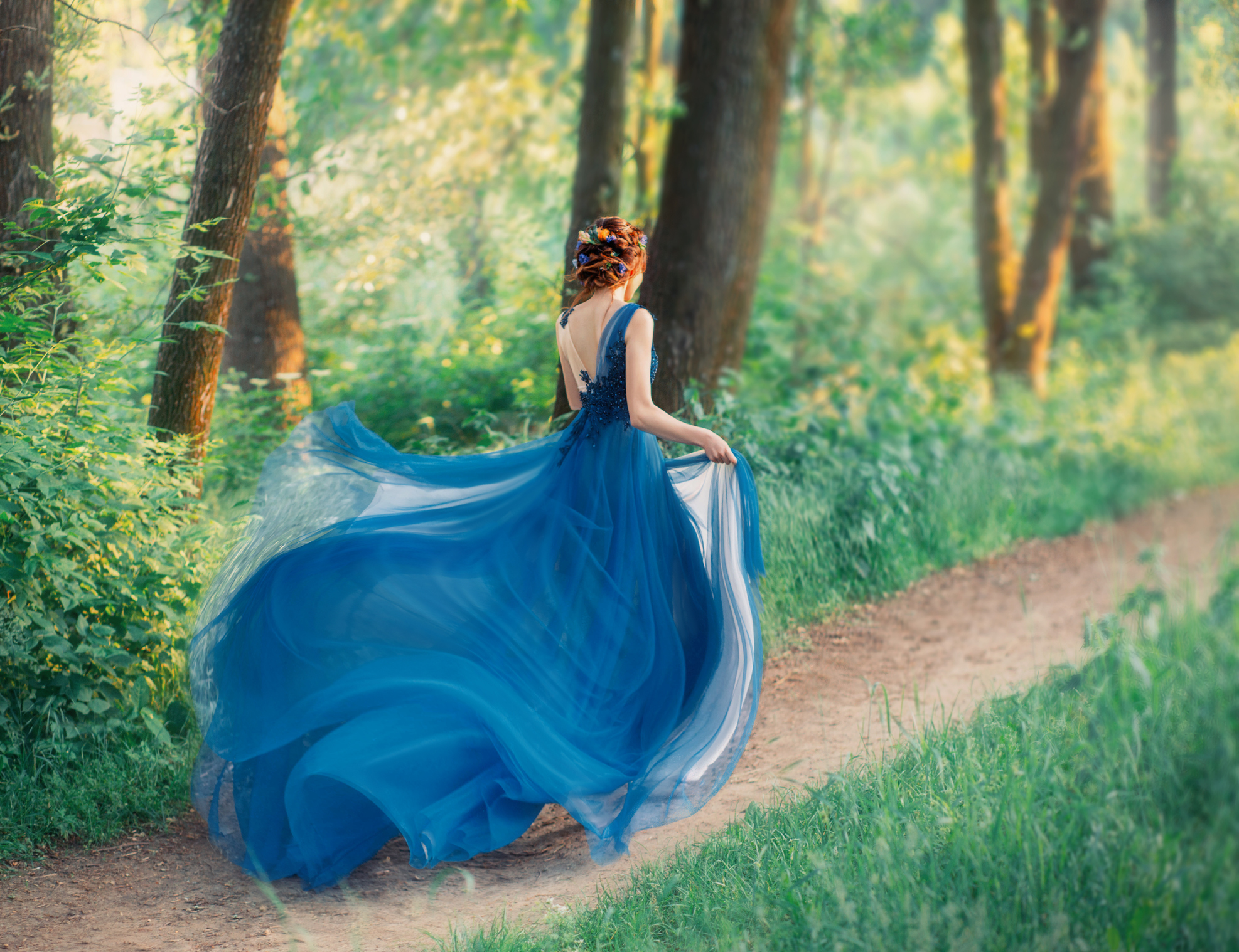 Lady in long elegant blue dress with flying light train